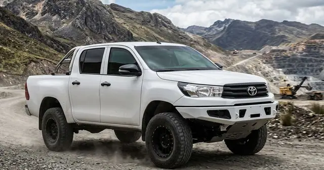 Camioneta Toyota Hilux blanca por un camino de mina en la montaña